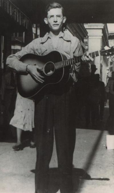 Hank Williams Sr. 1938- Hank Williams playing guitar on a sidewalk in Montgomery, Alabama.